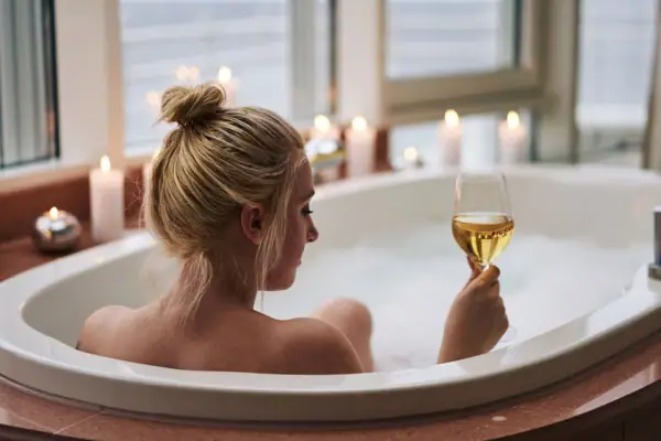 Badewanne Eine Frau in einer Badewanne hält ein Glas Wein.