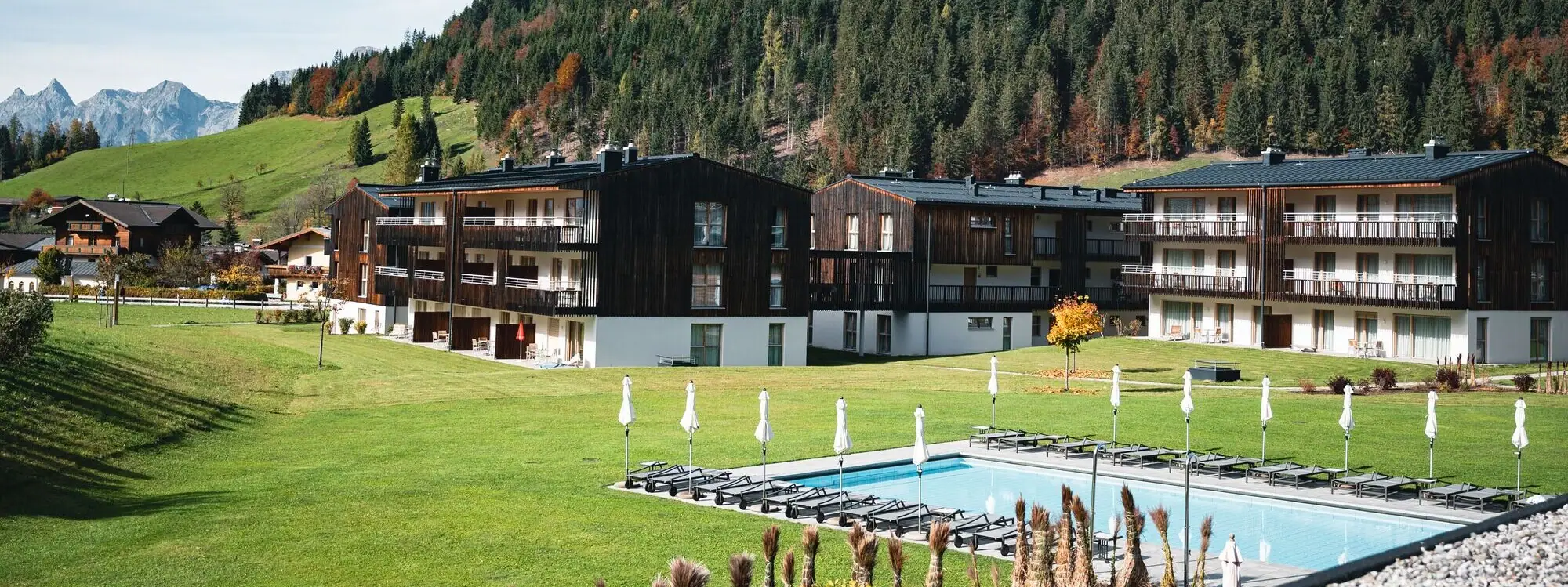Ein Pool vor Gebäuden mit Bäumen und einem klaren Himmel im Hintergrund.