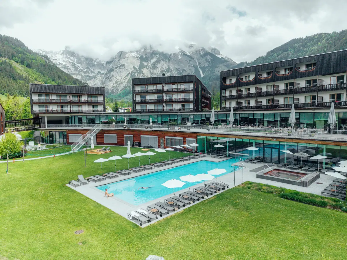 Ein Pool in einem Hotel mit Rasen und Bergen im Hintergrund.