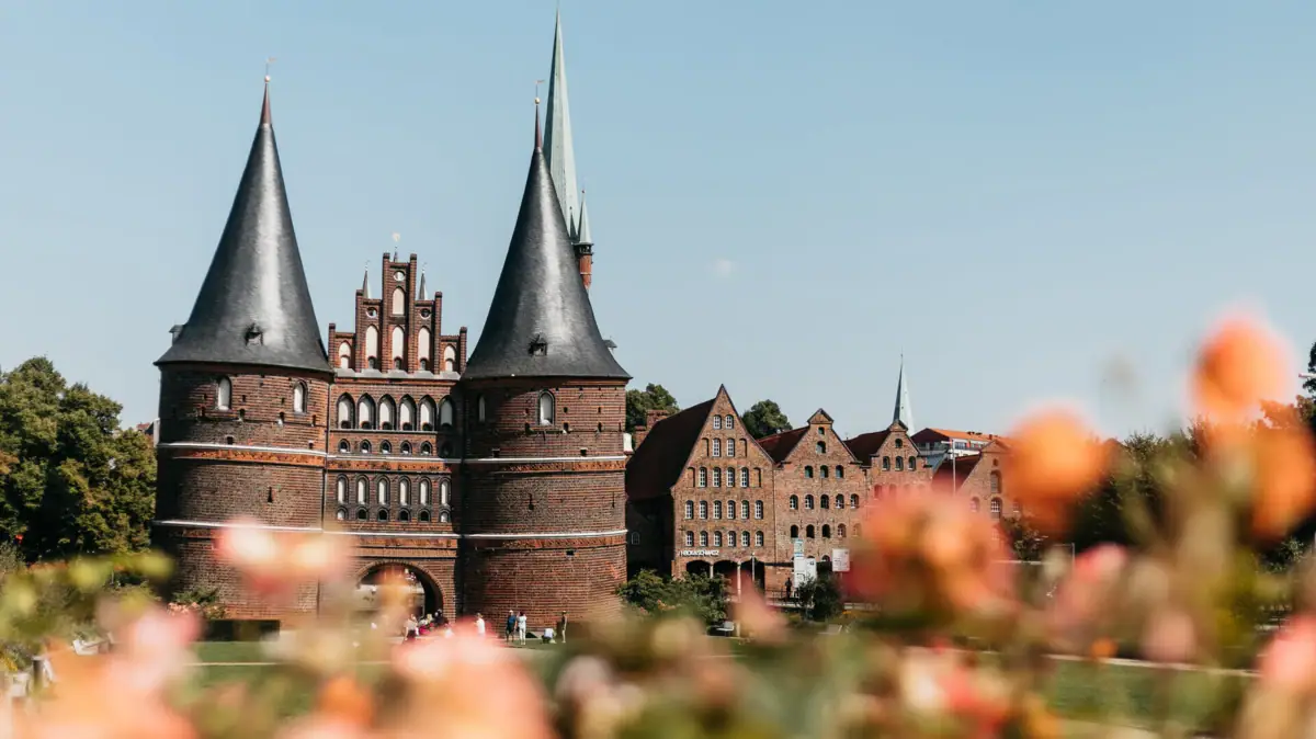 Holstentor Ein Gebäude mit Türmen und einem Rasen im Hintergrund.