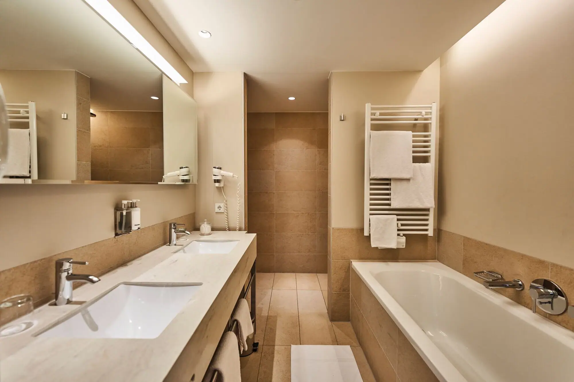 Badezimmer mit Badewanne und Waschbecken, ausgestattet mit Armaturen und Fliesen.