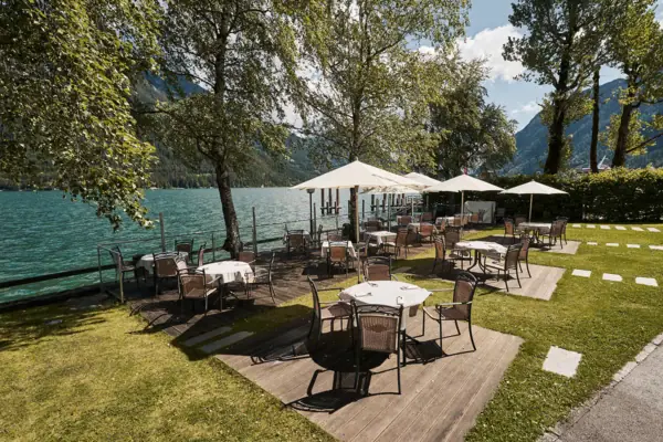 Ein Tisch und Stühle auf einem Deck am See.