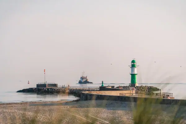 Warnemünde Leuchtturm am Strand vor blauem Himmel