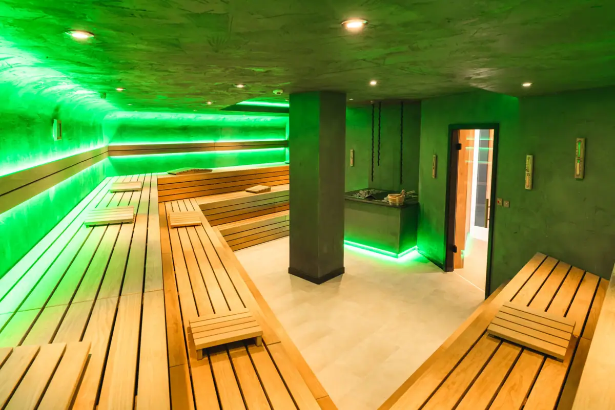 Sauna Eine Sauna mit grünem Licht und Holzbänken.