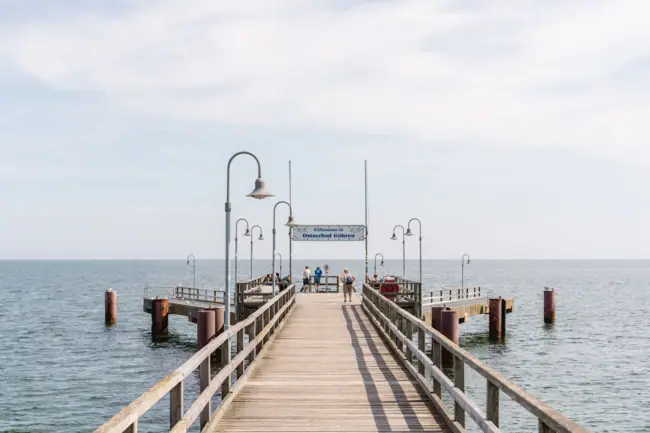 Seebrücke Sellin Holzsteg mit Menschen, die darauf spazieren gehen.