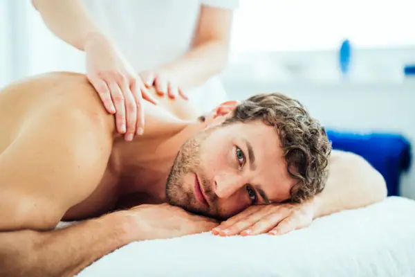 Massage Ein Mann liegt auf einem Massagetisch.