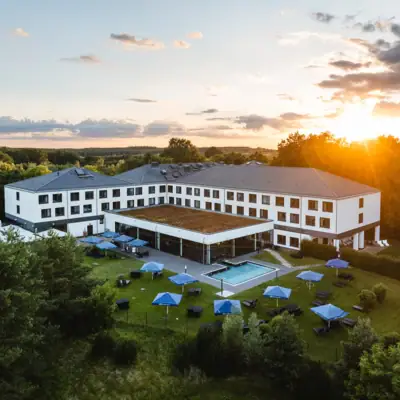 Ein Gebäude mit einem Pool und Sonnenschirmen in der Mitte.