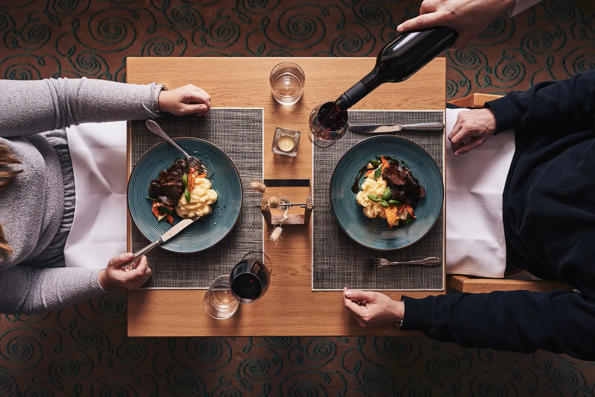 Eine Person hält eine Weinflasche und isst Essen.