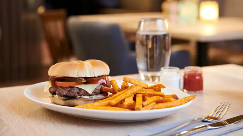 Buger Ein Teller mit Pommes frites und einem Sandwich auf einem Tisch.