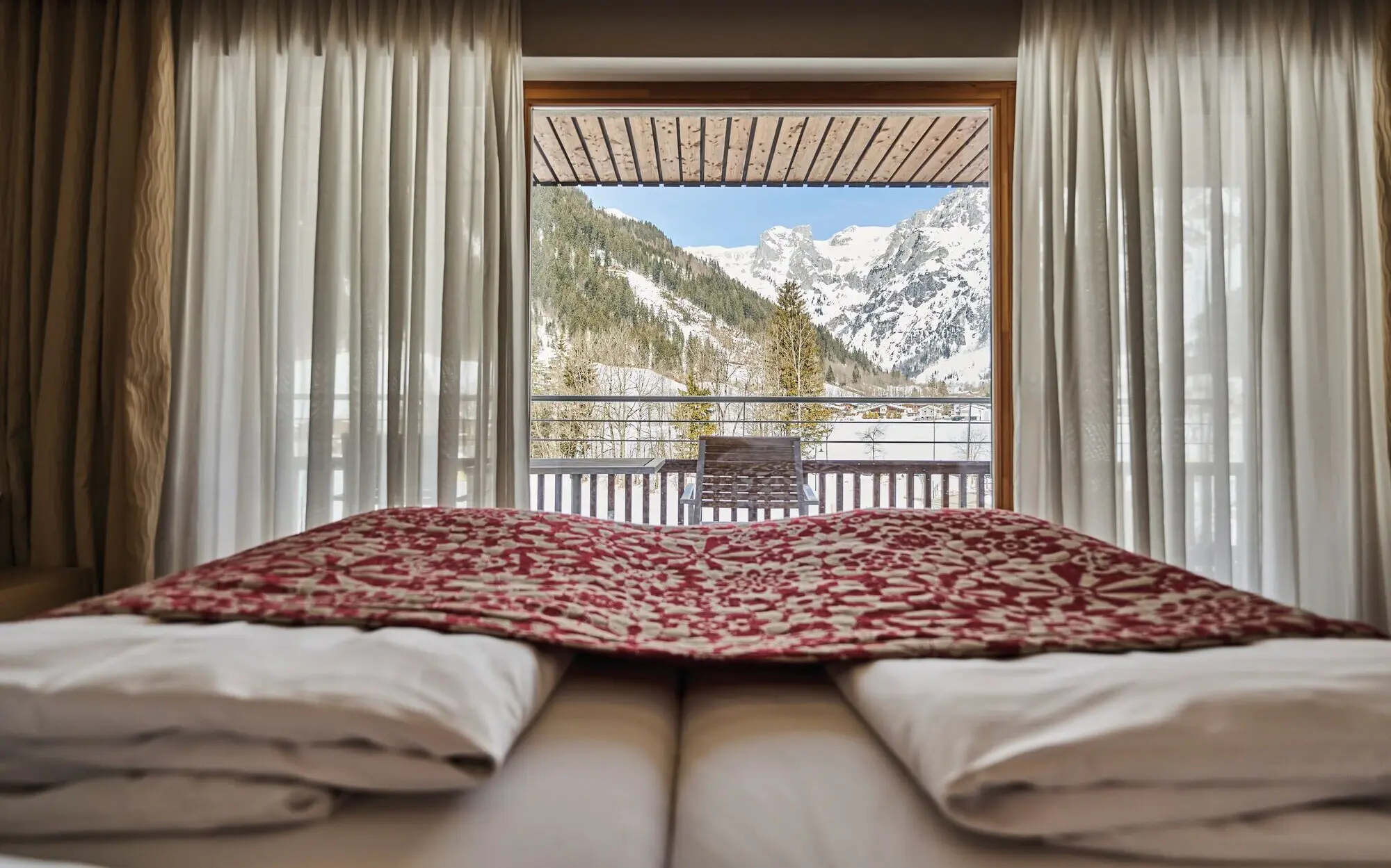 Ein Bett mit Blick auf die Berge, umgeben von gemütlicher Bettwäsche und Kissen.