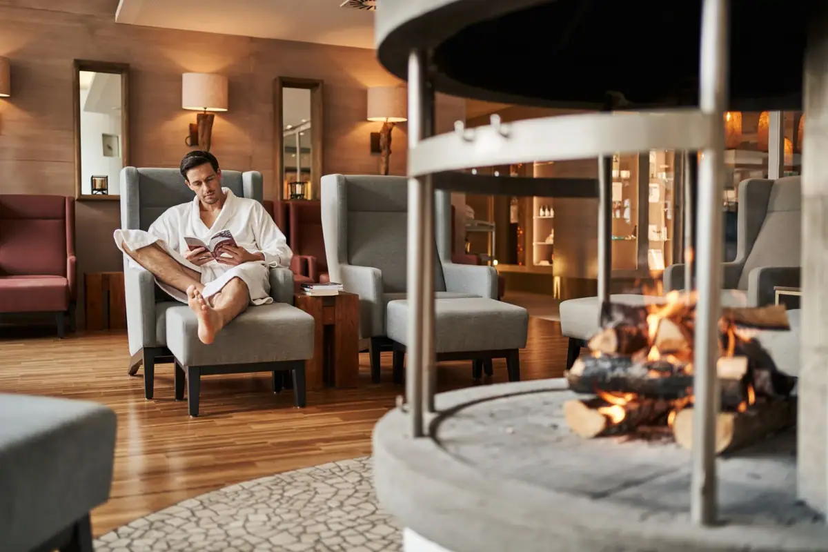 Ein Mann in einem Bademantel sitzt in einem Stuhl am Kamin.