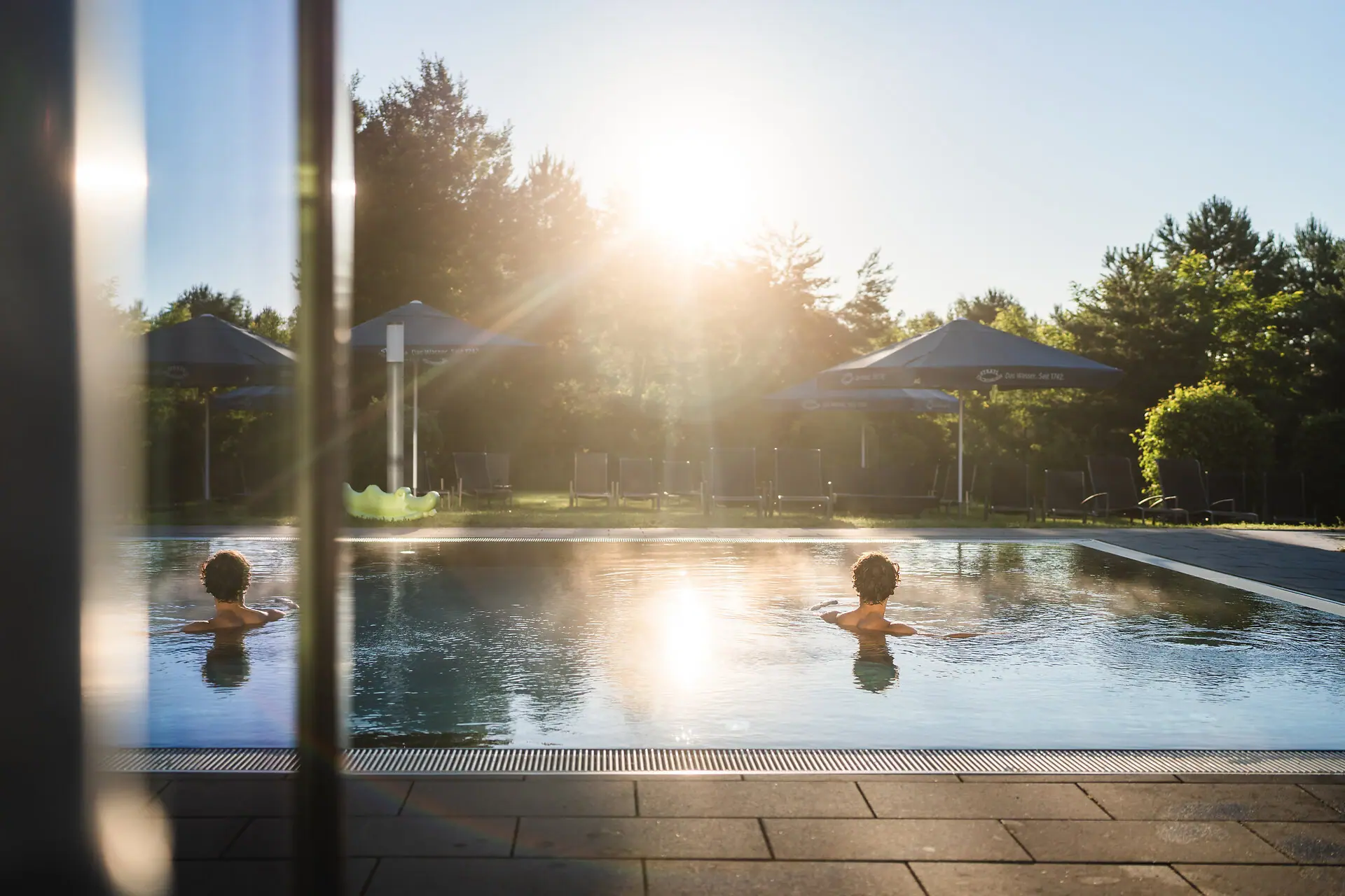 Außenpool Ein Mensch schwimmt in einem Außenpool bei Sonnenschein.