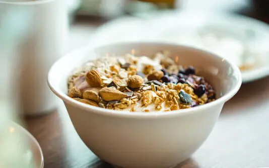 Eine Schüssel mit Müsli, Nüssen und Joghurt auf einem Tisch.