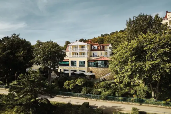 Außenansicht vom aja Bansin umgeben von grünen Bäumen an einem sonnigen Tag. 