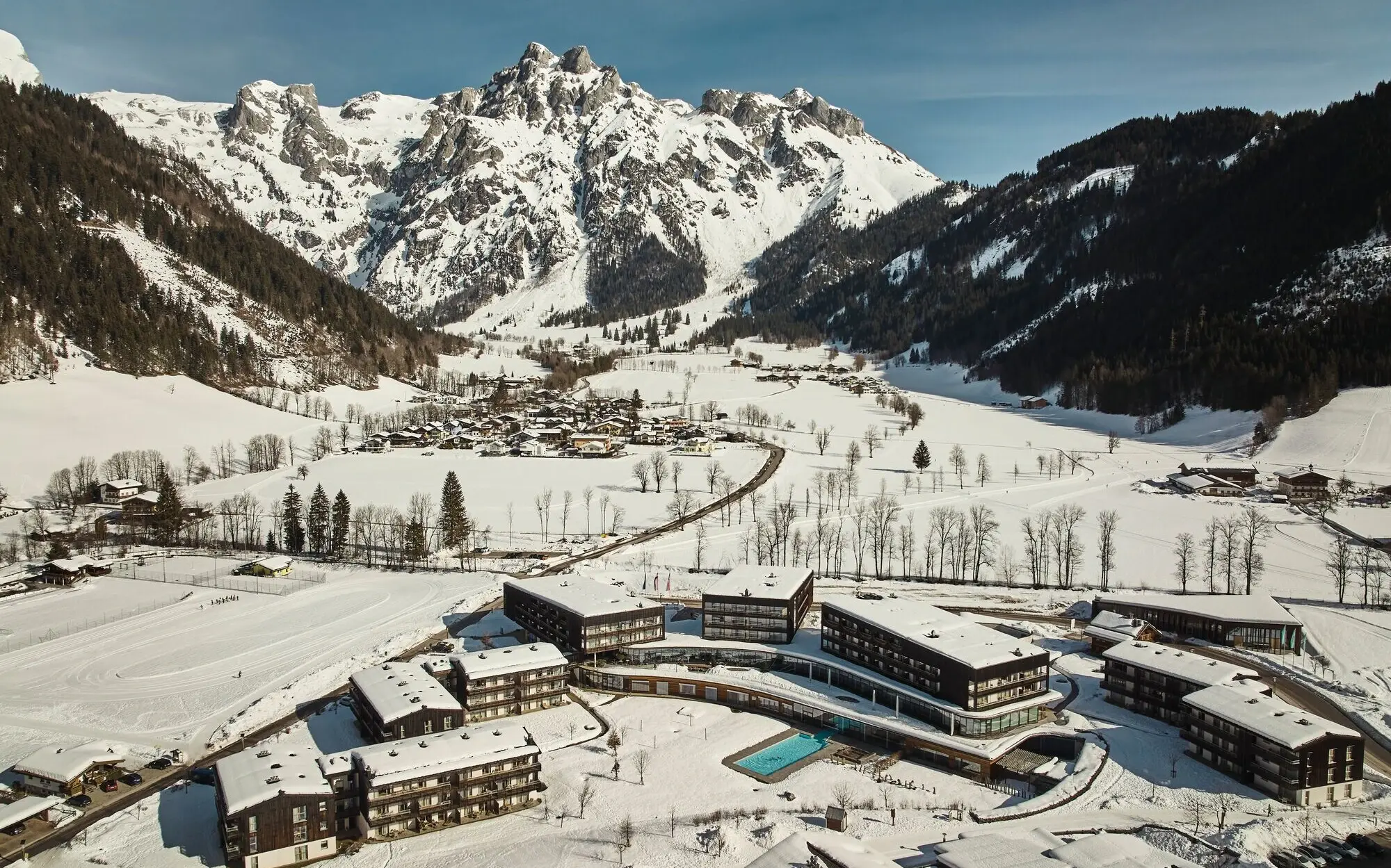 Gruppe von Gebäuden in einem verschneiten Tal mit Bergkulisse.