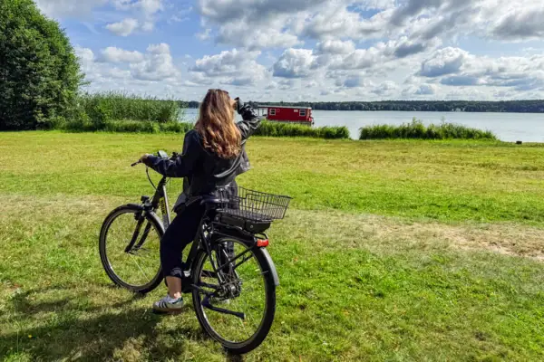 Fahrrad fahren am See Frau steht mit Fahrrad am See und schaut Richtung See.