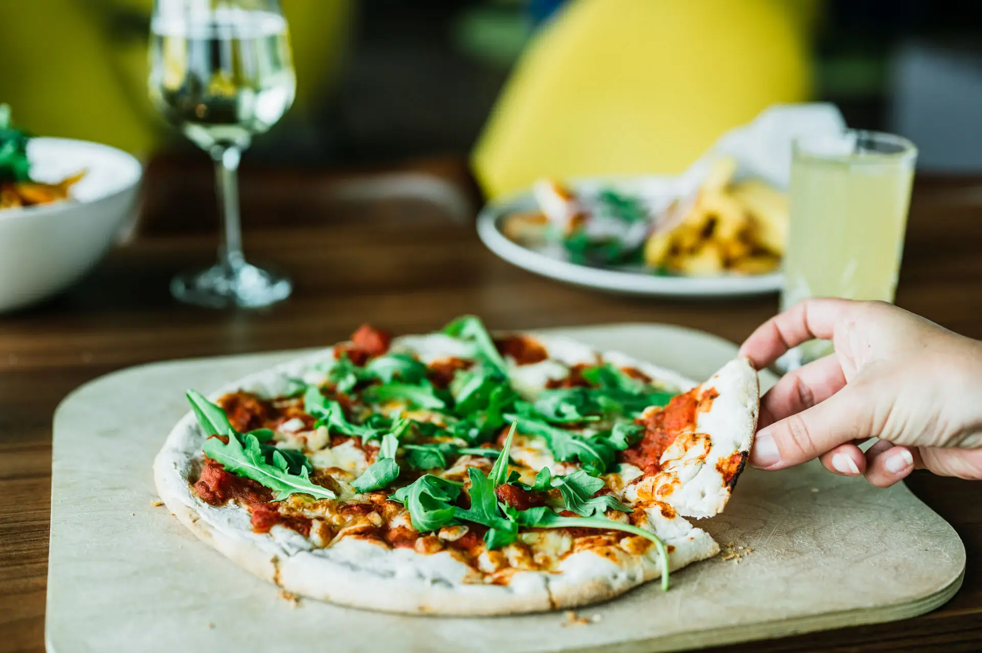 Eine Hand hält eine Pizza.