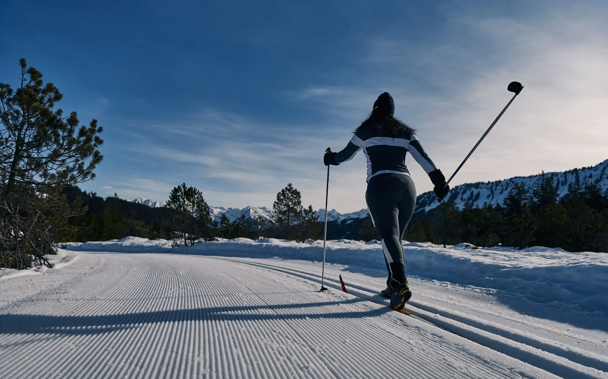 Person auf Skiern auf verschneiter Loipe.