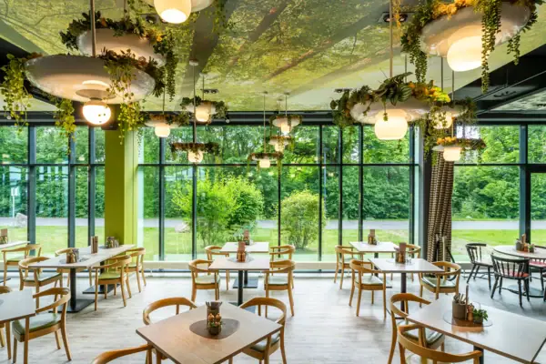 Ein Raum mit Tischen, Stühlen und Pflanzen, die von der Decke hängen.