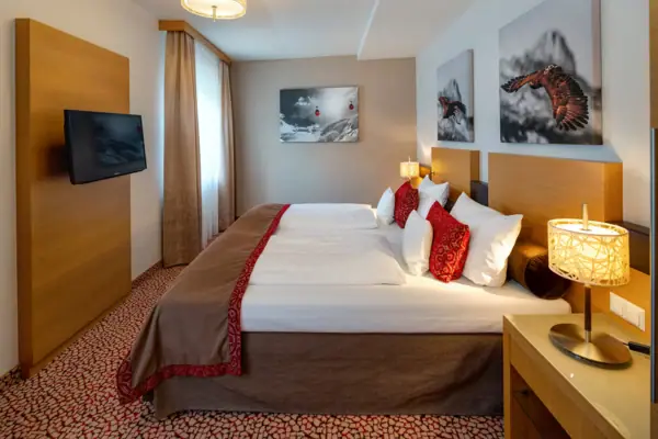 Ein Bett mit Kissen und einem Fernseher in einem Hotelzimmer am Achensee.