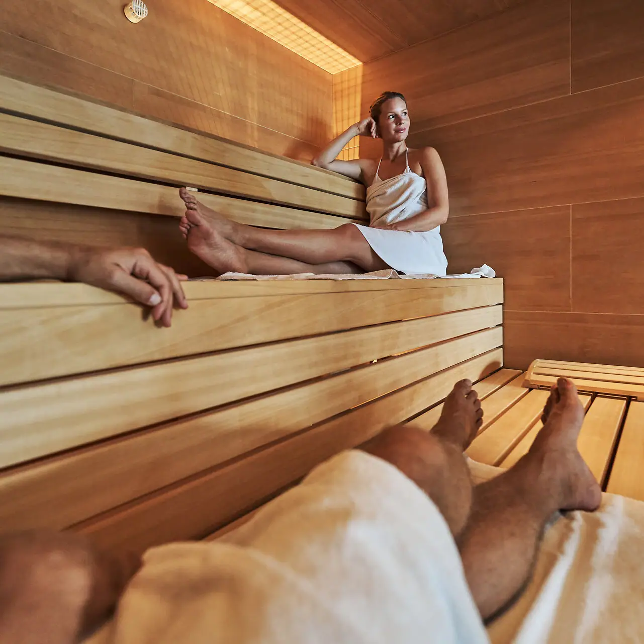Sauna Eine Frau sitzt auf einer Holzbank in einer Sauna.