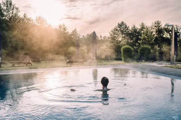 Eine Frau in einem Pool mit Bäumen und bewölktem Himmel.