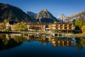 aja Fürstenhaus am Achensee Ein Gebäude neben einem Gewässer mit Bäumen im Hintergrund.