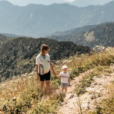 Eine Frau und ein Kind beim Wandern auf einem Berg.