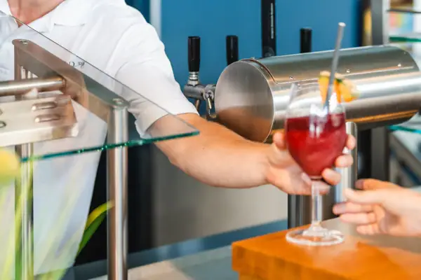 Ein Mann reicht einem Kunden ein Getränk.