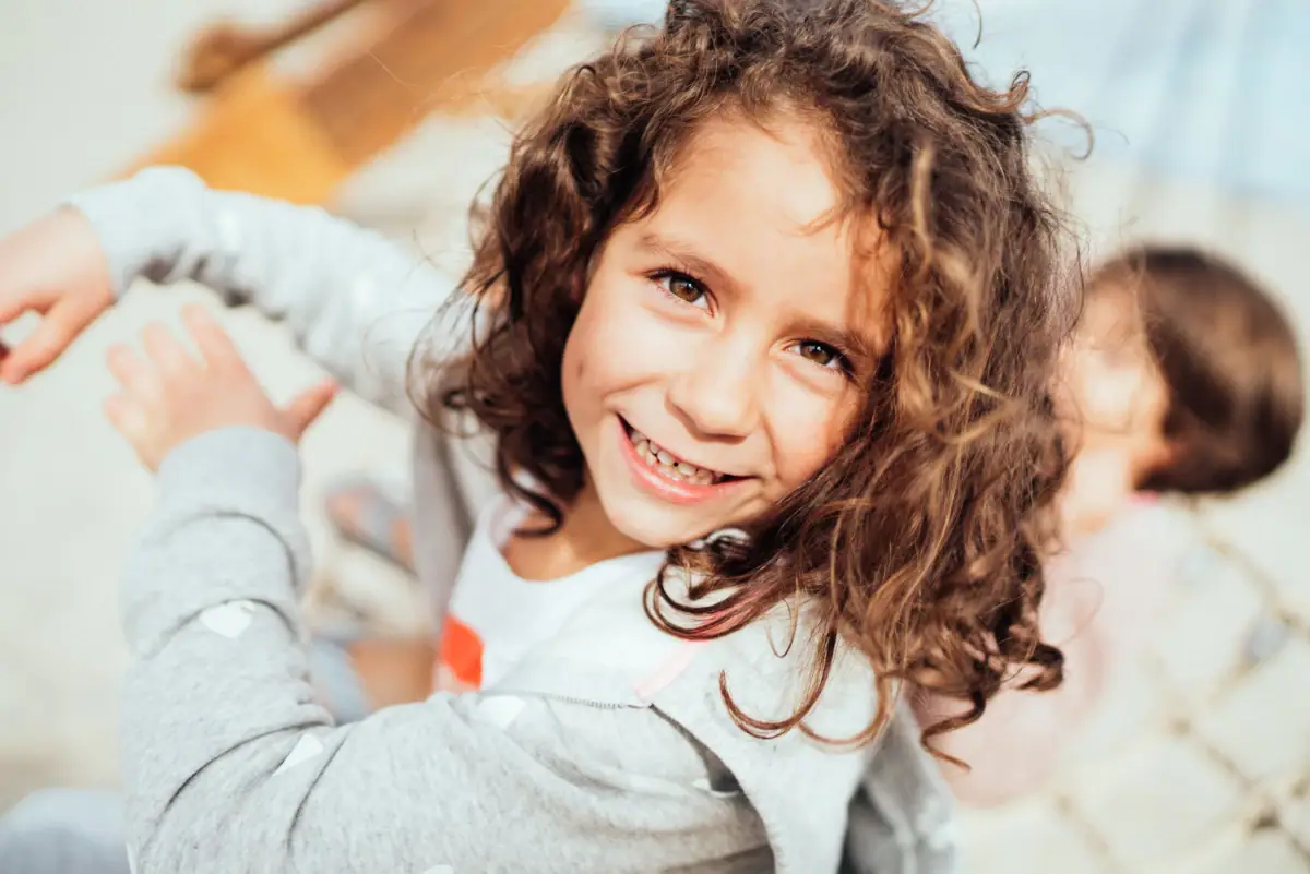 Ein Mädchen mit lockigem Haar lächelt.