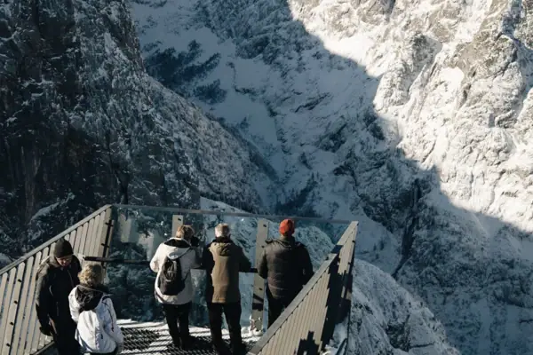 Eine Gruppe von Menschen auf einer Brücke über einem verschneiten Berg.
