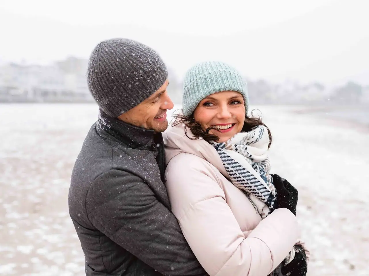 Ein Mann und eine Frau umarmen sich im Schnee.