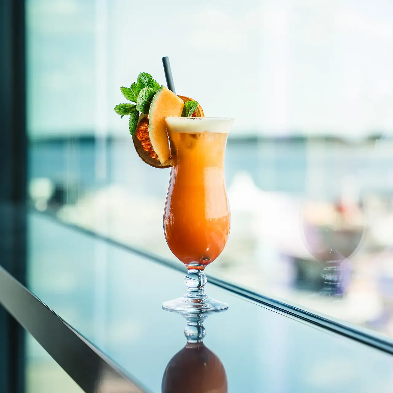 Cocktail Ein Glas mit einem Cocktail und einer Garnierung auf einem Tisch.