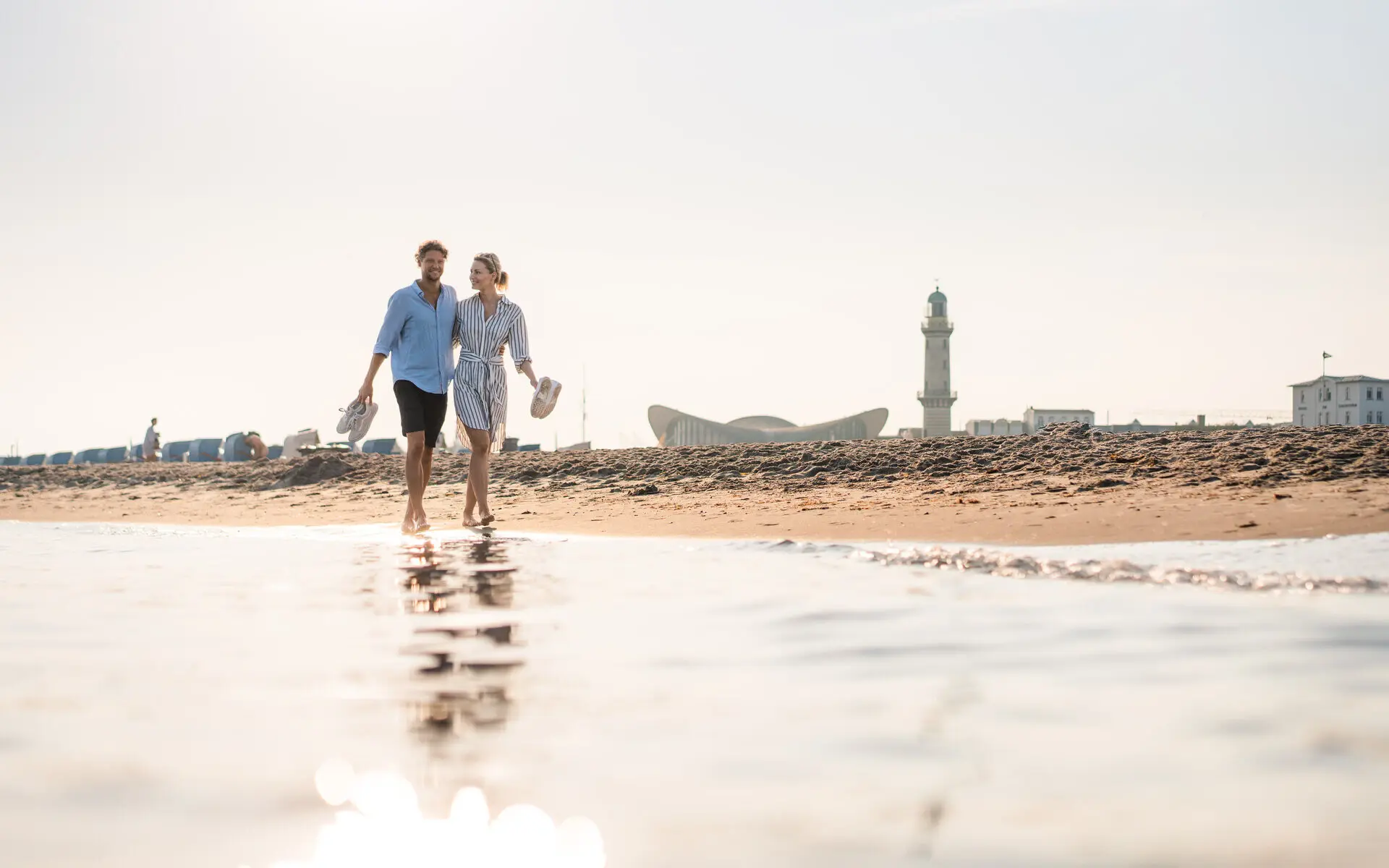 Ein Mann und eine Frau gehen am Strand entlang.