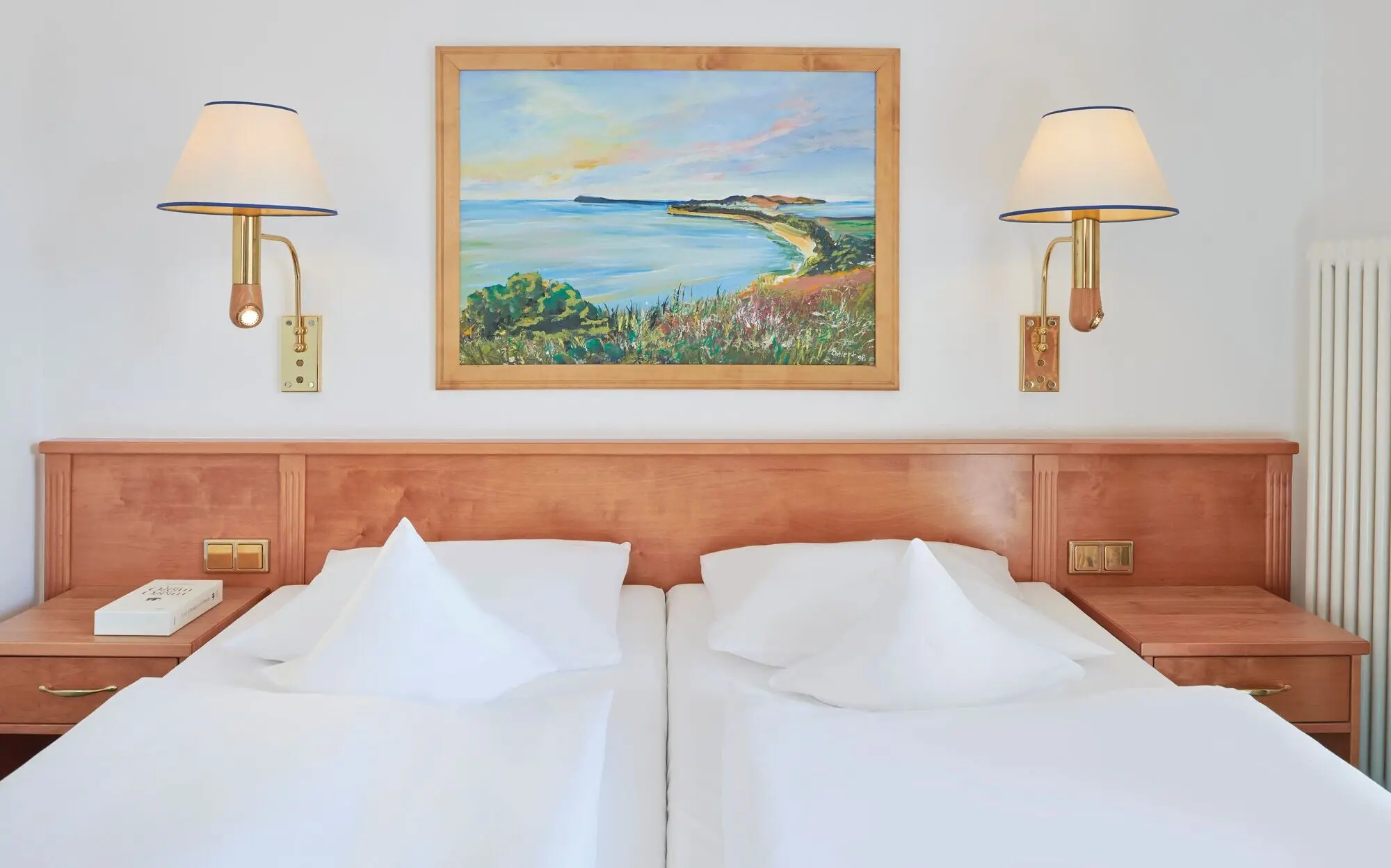 Bett mit weißen Laken und einem Gemälde an der Wand.