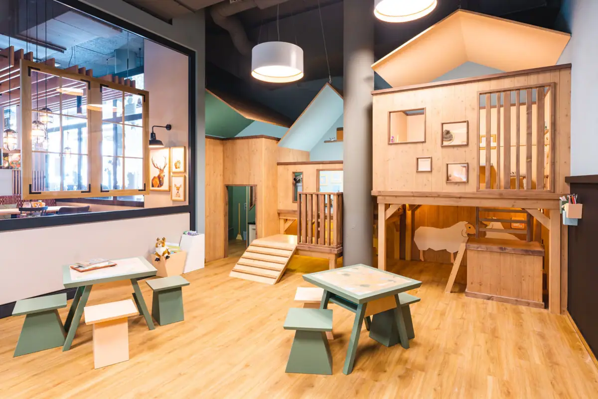 Kinderbereich Ein Raum mit Holzmöbeln und einem Spielhaus.