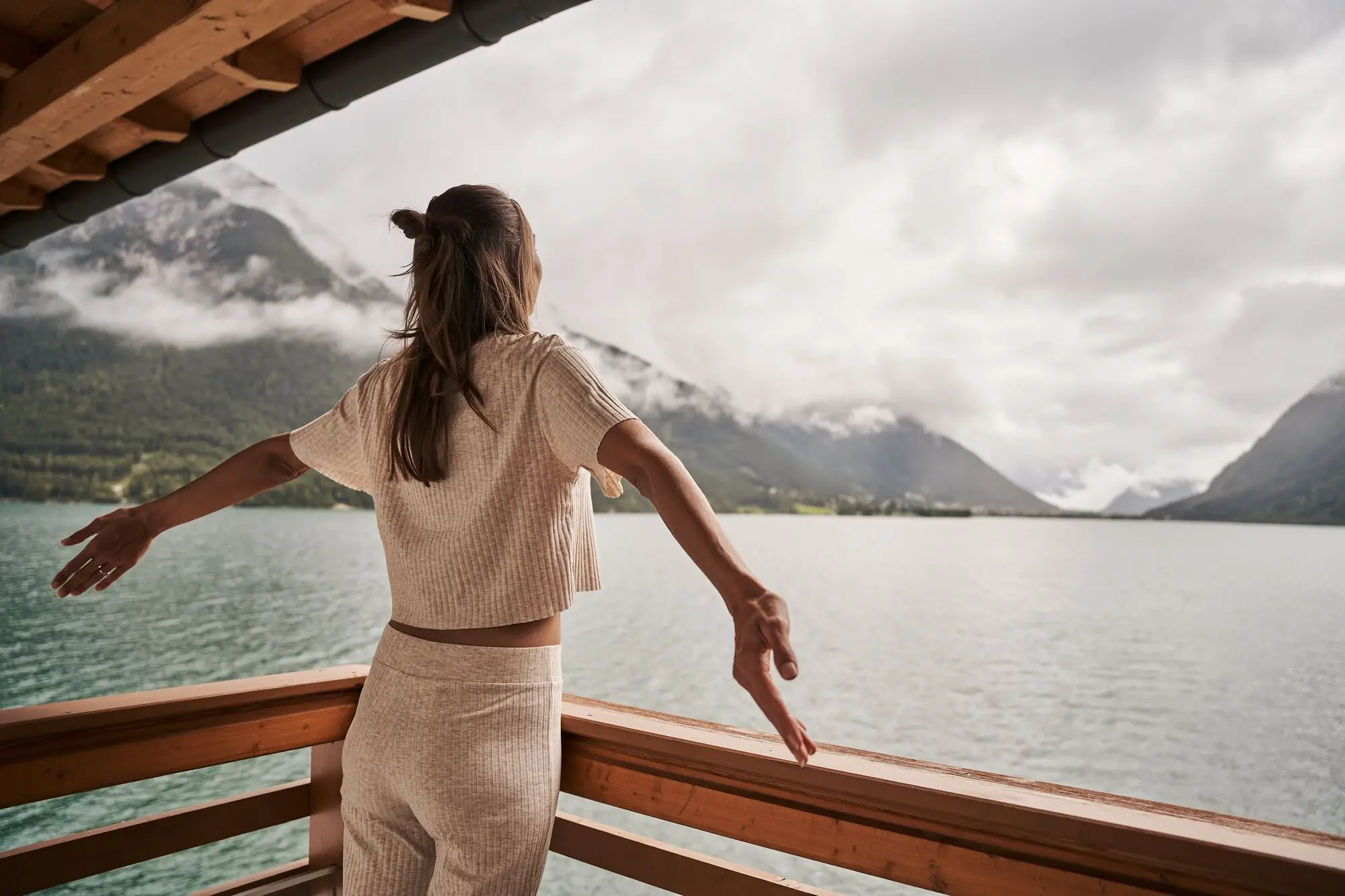 Frau steht auf einer Holzplattform und blickt über den Achensee.