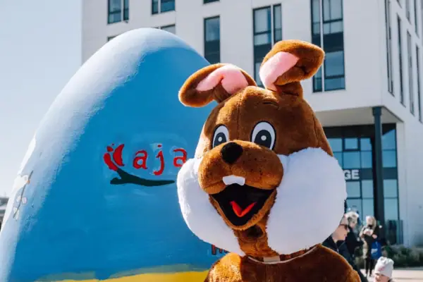 Person in einem Hasenkostüm neben einem Ei