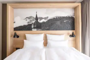 Junior Suite Bergblick Bett mit weißen Kissen und einem Bild darüber