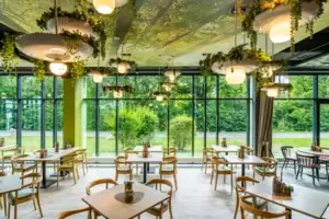 Restaurant Ein Raum mit Tischen und Stühlen, Pflanzen hängen von der Decke.