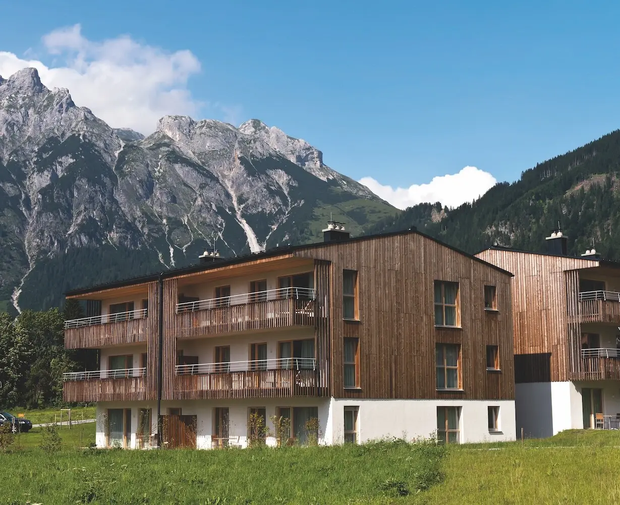 Building with mountain in the background and surrounded by trees and grass.