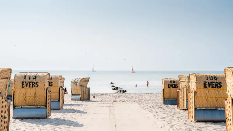 Strand mit vielen Stühlen und einem Gewässer im Hintergrund
