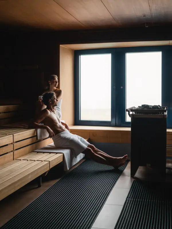 Sauna im aja Warnemünde Ein Mann und eine Frau sitzen in einer Sauna.