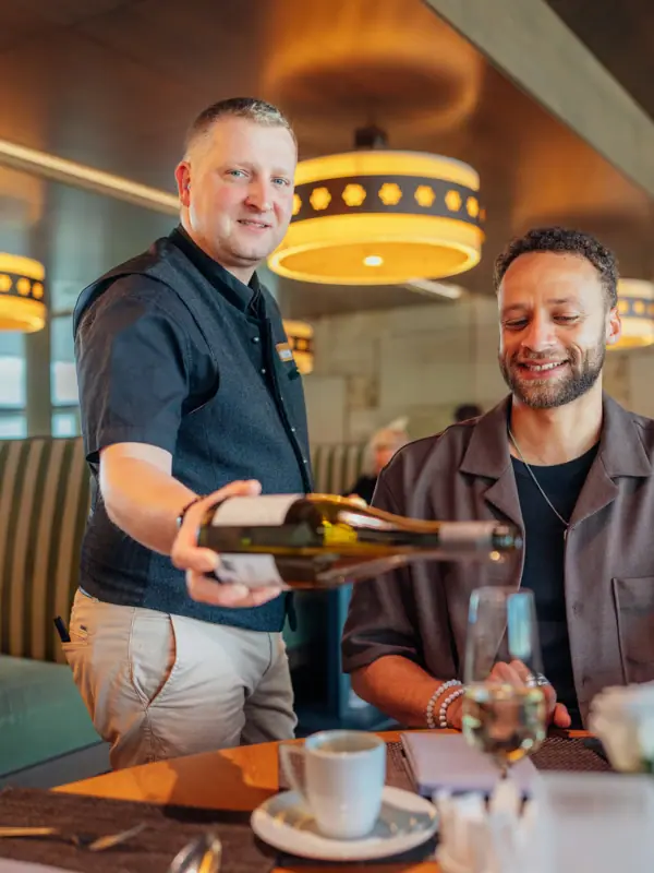 Wein im Feinspitz Ein Mann schenkt Wein in ein Glas ein.