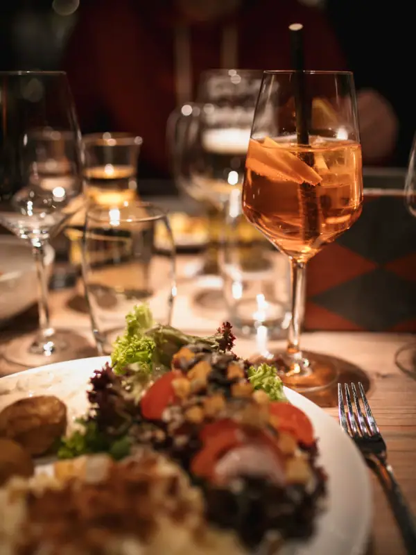 Ein Teller mit Essen und ein Weinglas mit Getränk auf einem Tisch.