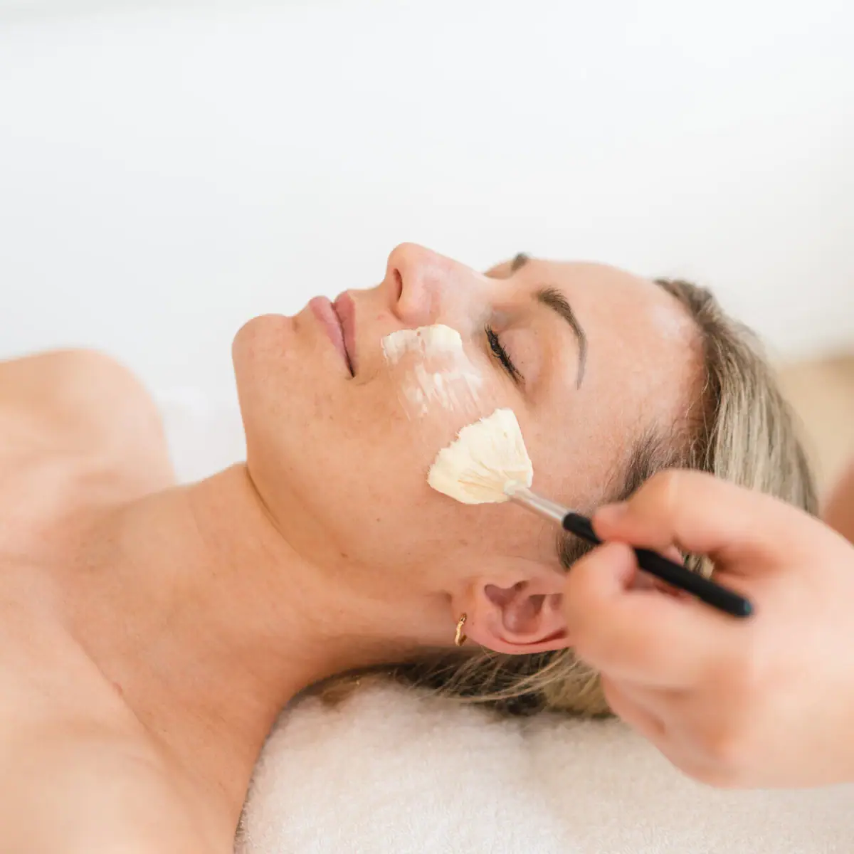 Gesichtsanwendung Eine Frau liegt mit einem Pinsel im Gesicht.