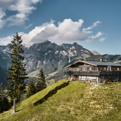 Werfenweng Berge Eine Hütte auf einem Hügel vor einem Bergpanorama.
