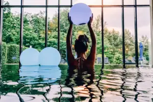 Innenpool Bad Saarow Eine Frau im Pool hält einen Ball.