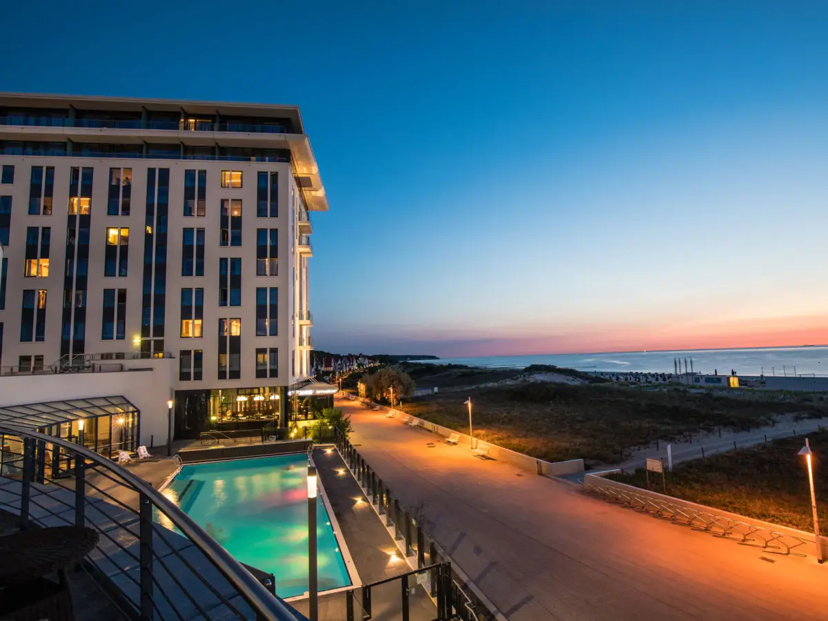 Das Hotelgebäude mit einem Pool und einem Gehweg am Meer.
