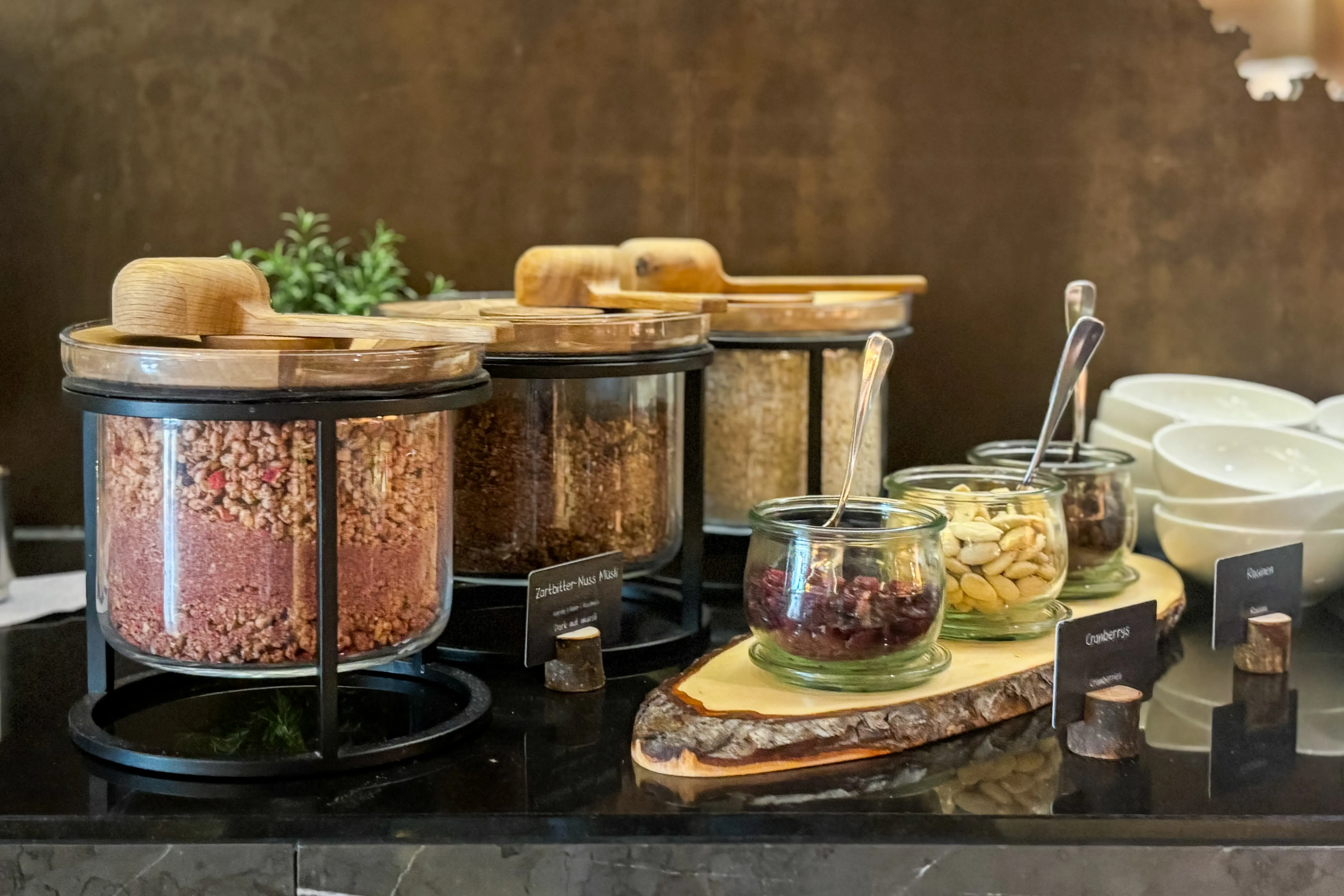 Ein Tresen mit verschiedenen Arten von Müsli in Behältern. Daneben stehen Nüsse und Kerne.